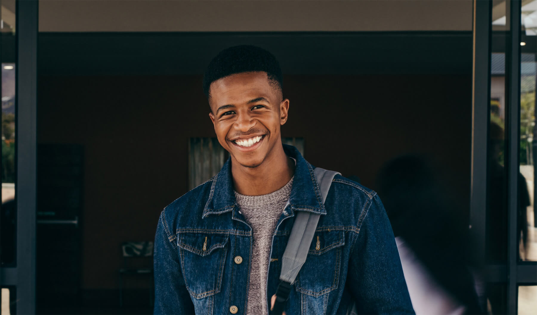 Black male student smiling in denim jacket