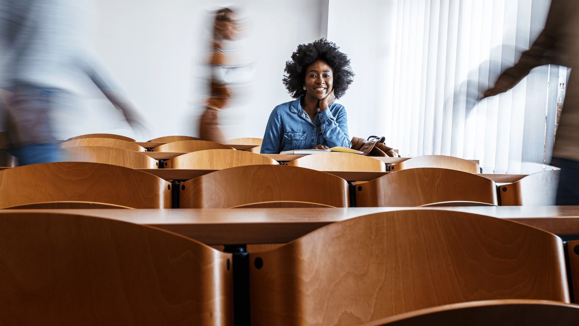 student smiling in wooden desk setup college