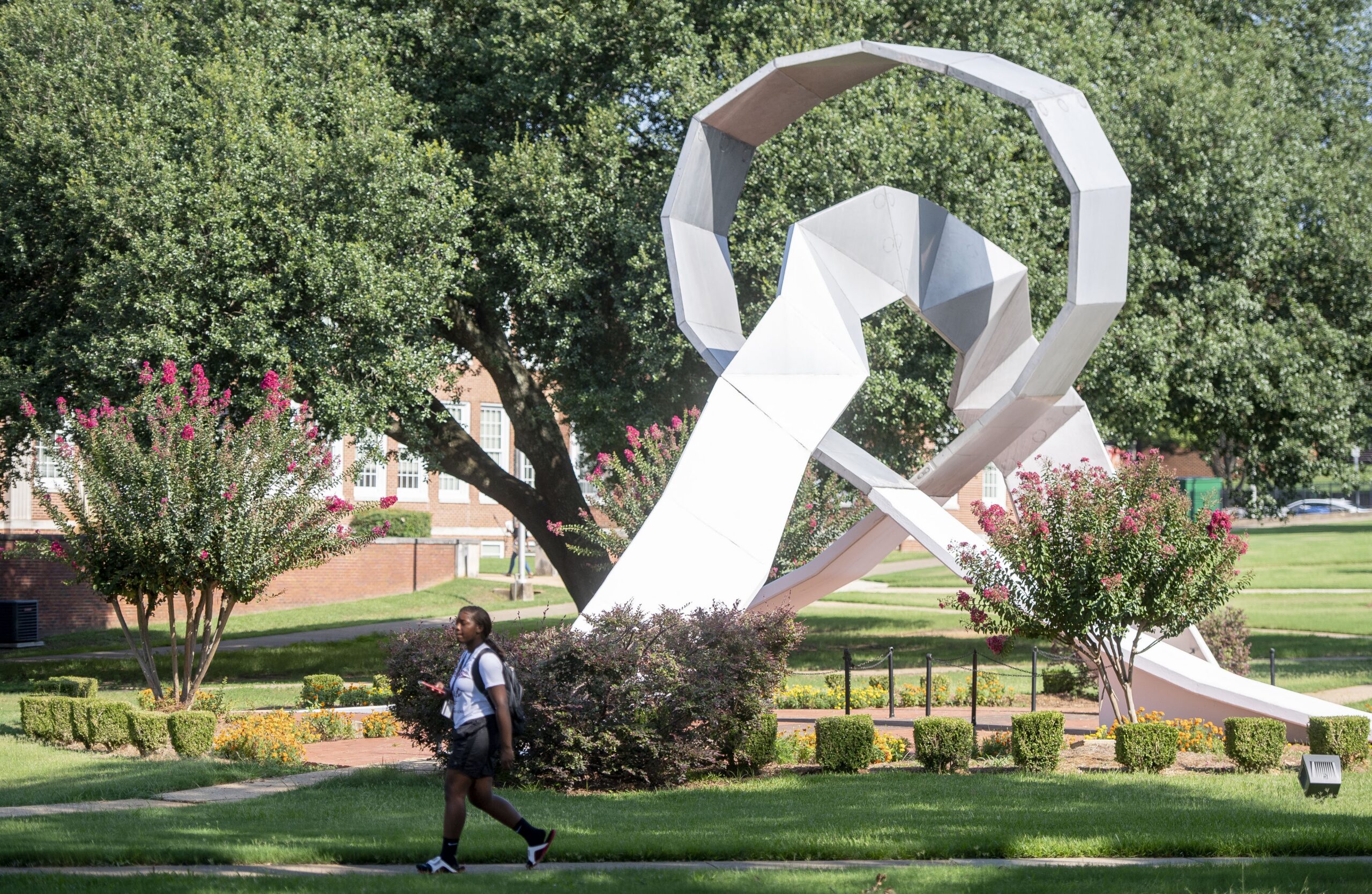 A student at Alabama State University walking by a campus structure, called The Equinox